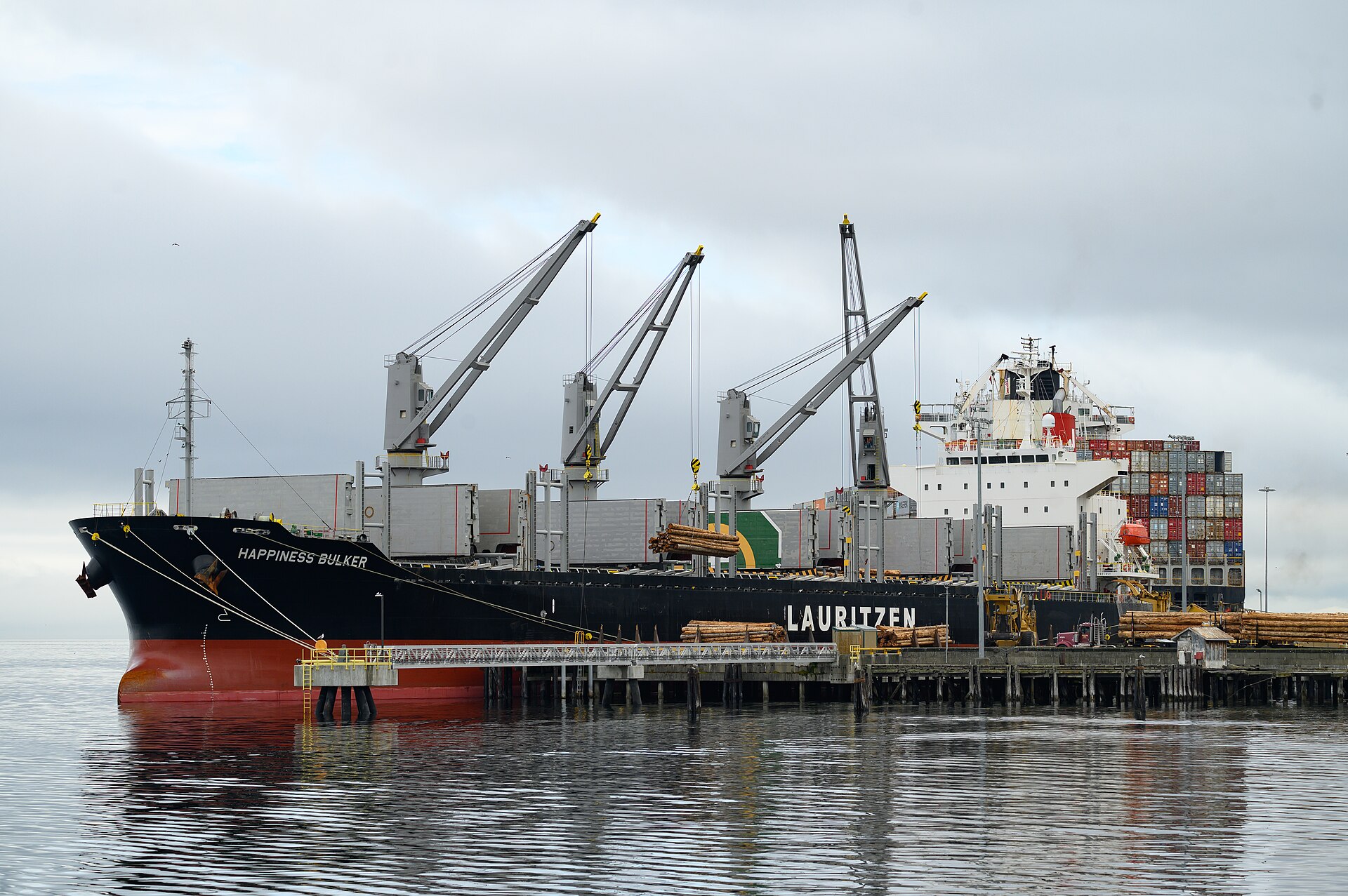 Navio graneleiro com guindastes de bordo atracado em píer